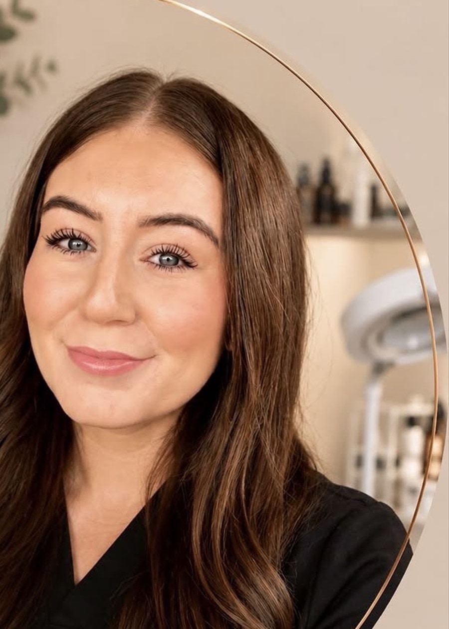 Mariah Elliott, a licensed Master Esthetician, wearing black professional attire in a skincare treatment room.